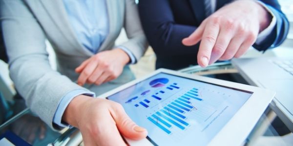 two business people in suits working side by side on a tablet