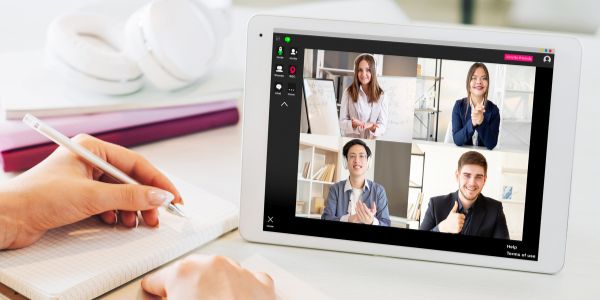 Person speaking to two female and two male executives through online app on a white ipad