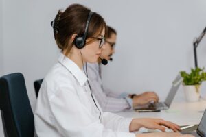 Company representatives with headsets working at their computers.